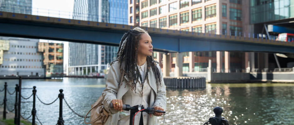 woman-at-a-city-looking-out-at-the-river-with-buildings-bridge-in-the-background